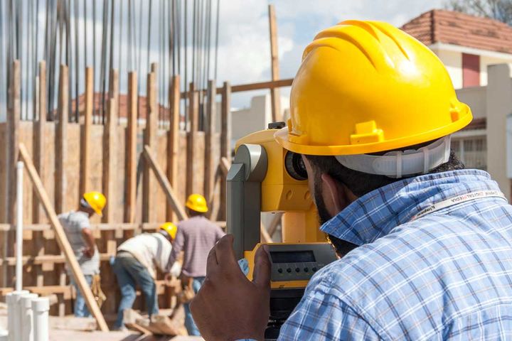 Close-up of an optical level operated by a member of the firm in a yellow hard hat