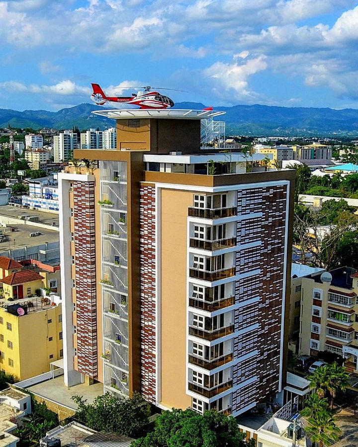 Aerial view of a residential tower with a helipad and a helicopter on the roof