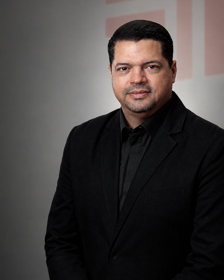 Andrés Torres in a black jacket and shirt, against a dark gray background