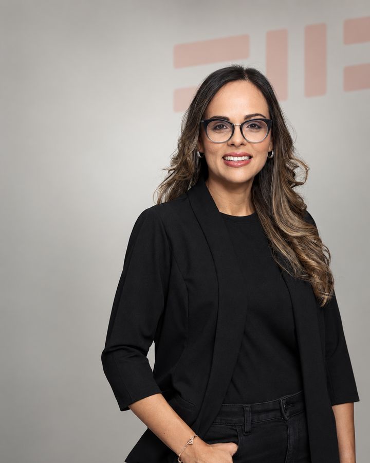 Mariel Tejada in an open black jacket, against a gray background