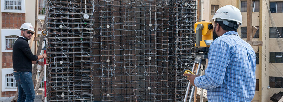 Deux personnes du cabinet effectuant des mesures au théodolite sur un chantier